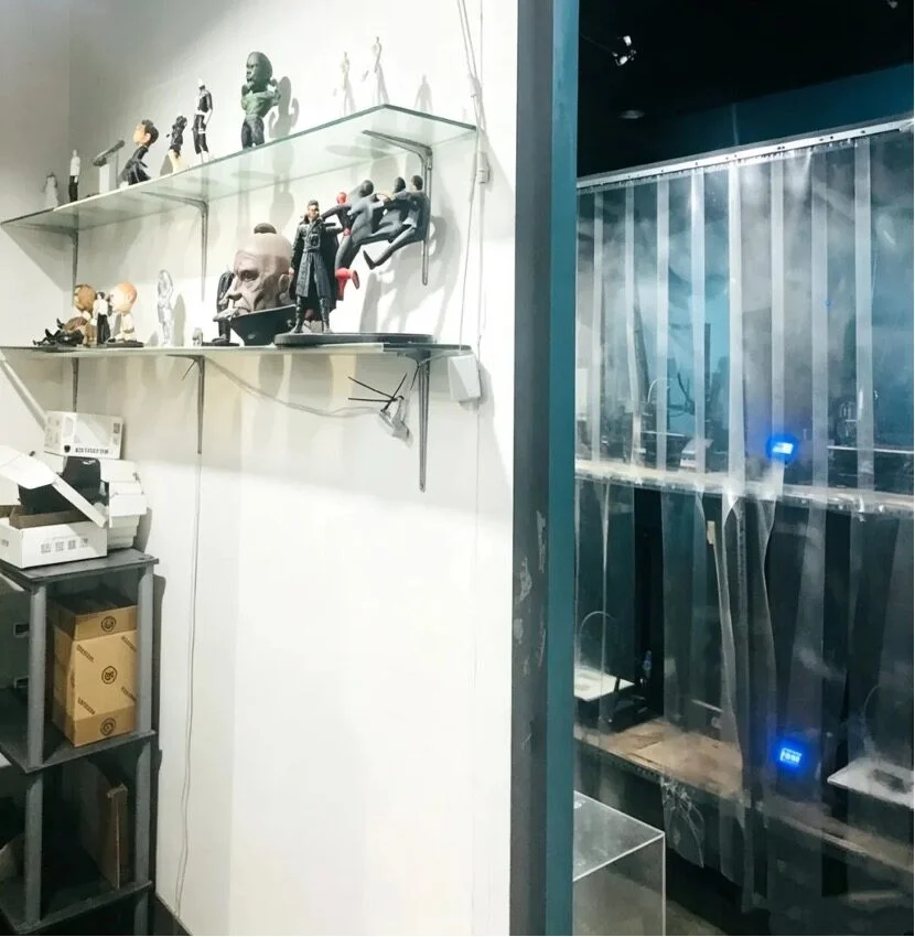 Стеллажи с фигурками и полки с коробками в офисе 3D-печати.