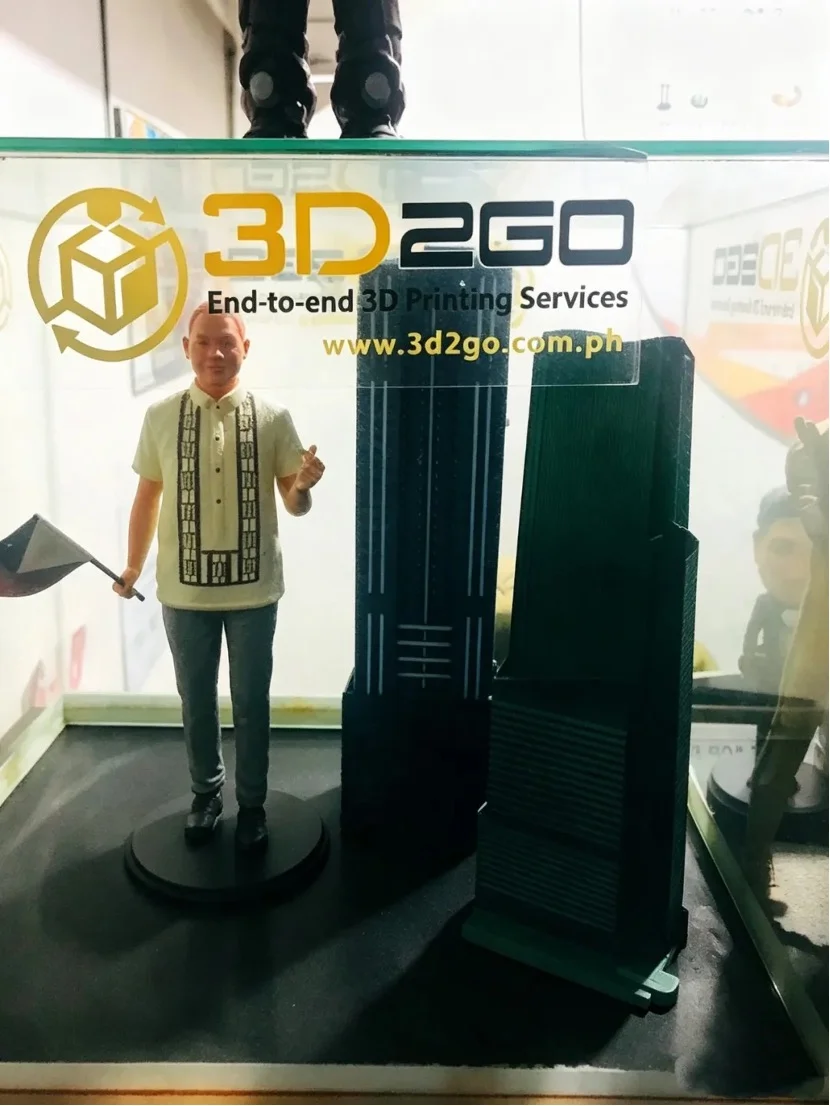 3D-печатная фигурка человека в традиционной филиппинской одежде рядом с миниатюрными небоскребами